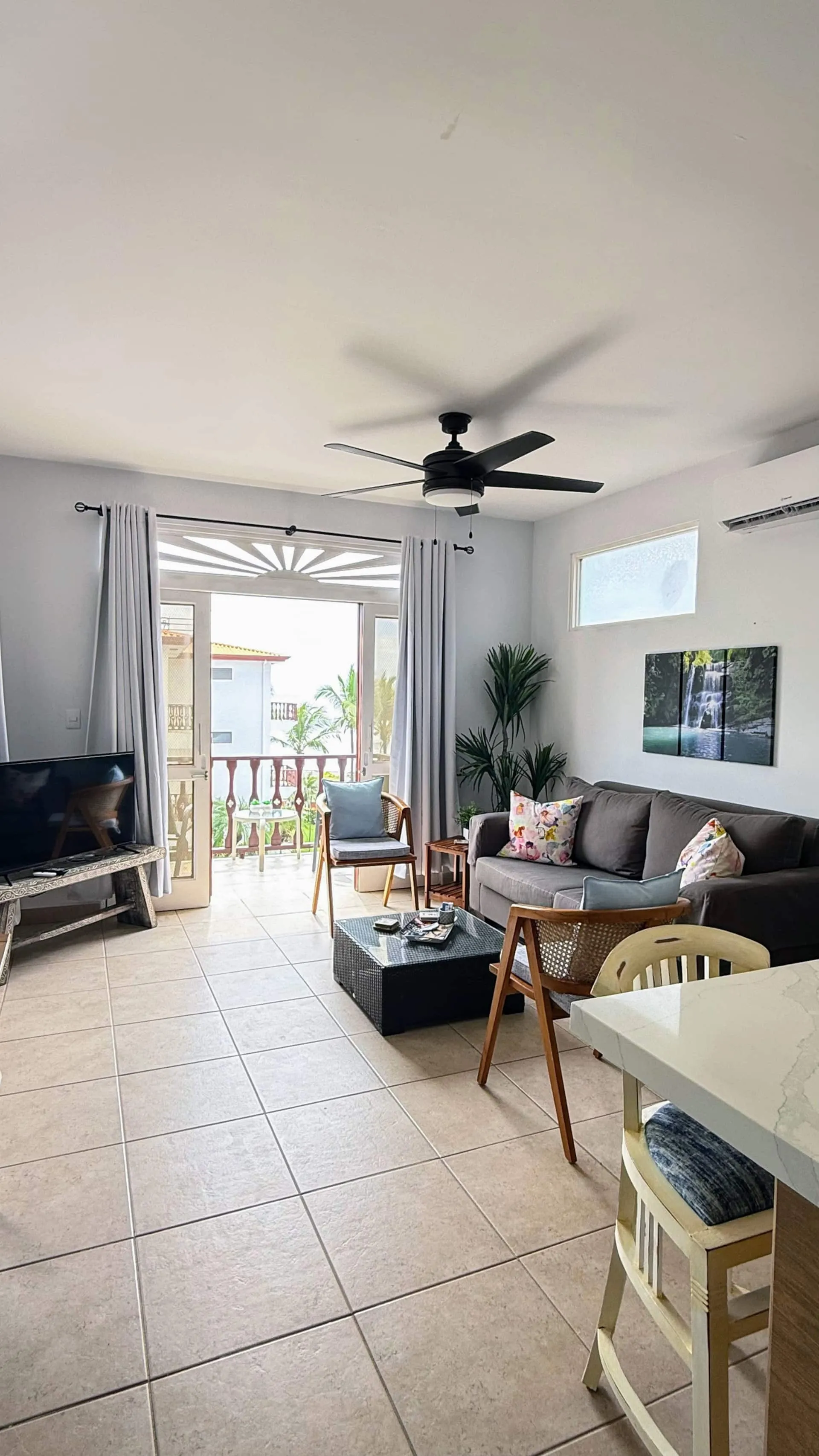 Living room with ceiling fan and glass doors opening onto the ocean-view balcony.