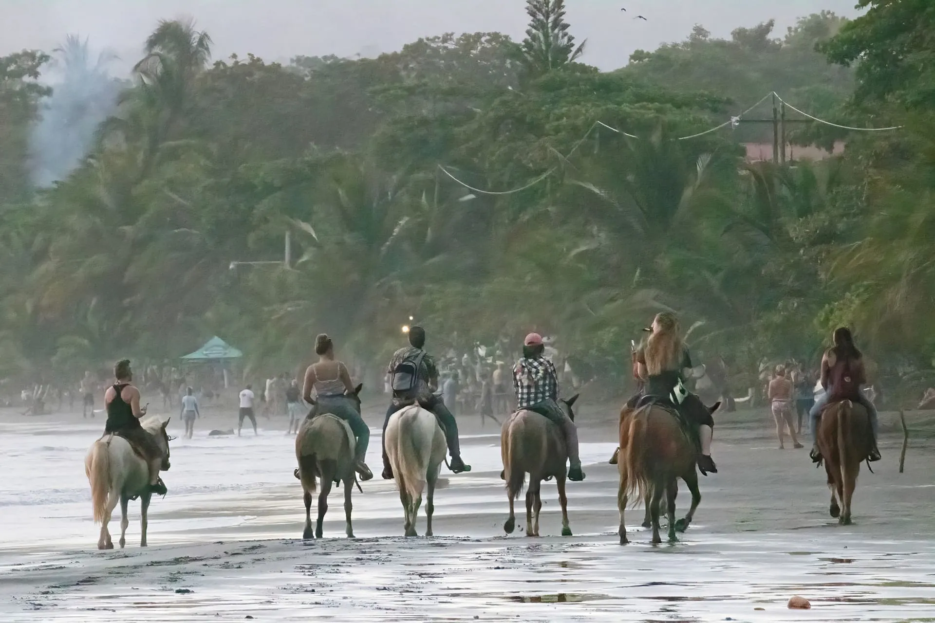 Horseback riders on Jacó Beach at dusk.